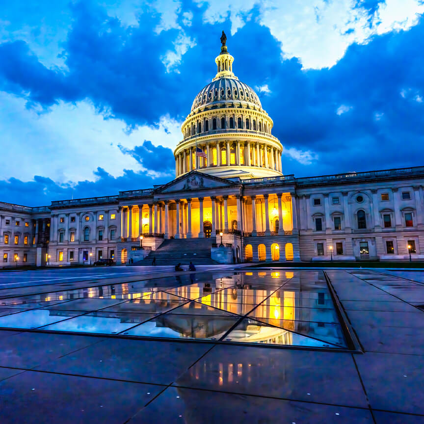 Image of capital in D.C. with blue cloudy sky and rain puddles